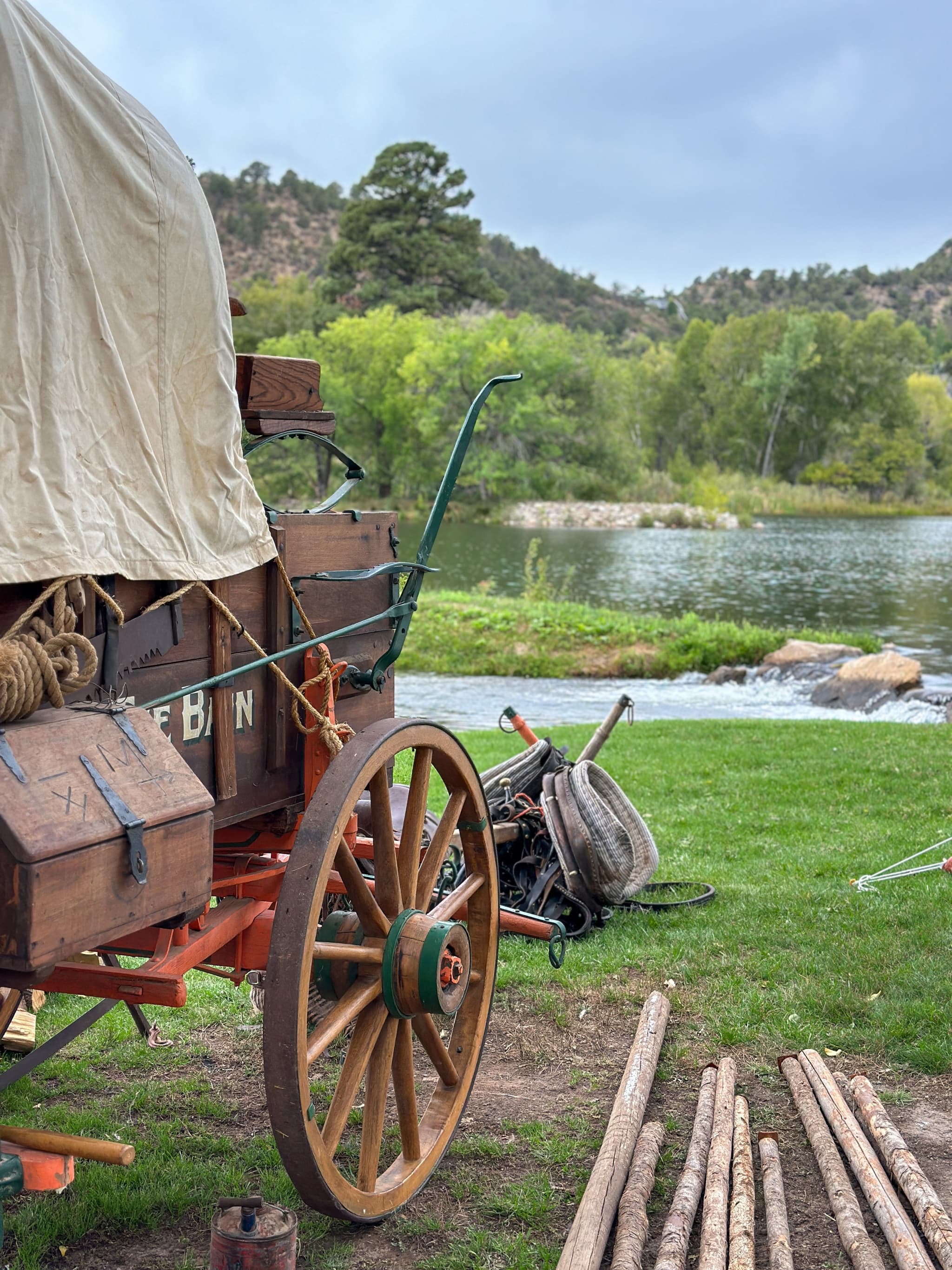 Rustic chuckwagon with canvas cover and wooden wheels beside LePlatt's Pond