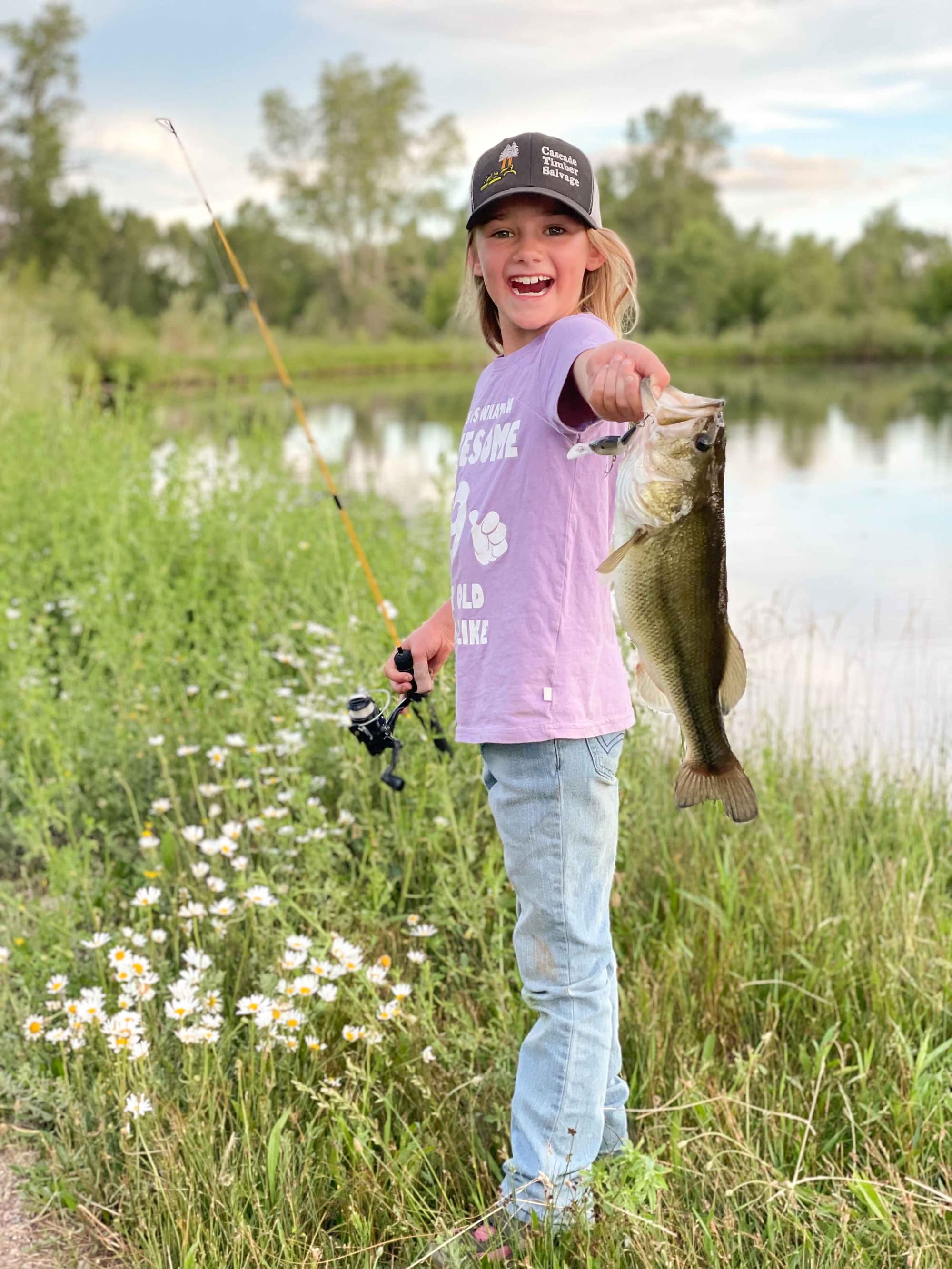 Young girl holding a bass caught at the pond