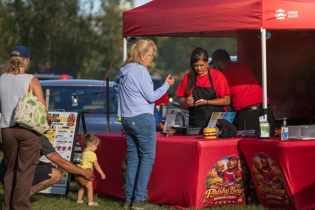 Guests ordering fresh burgers at the Phishy Bear Burger Stand beneath its red canopy