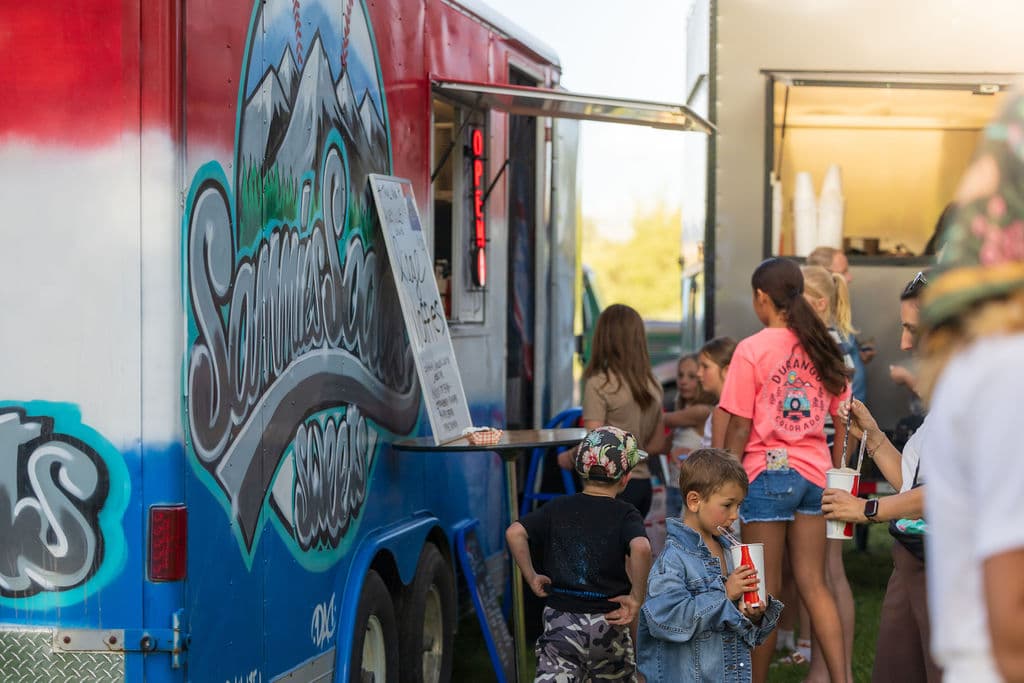 Children gathering at the Sammies Sodas truck for cold drinks and sweet treats in the evening sun