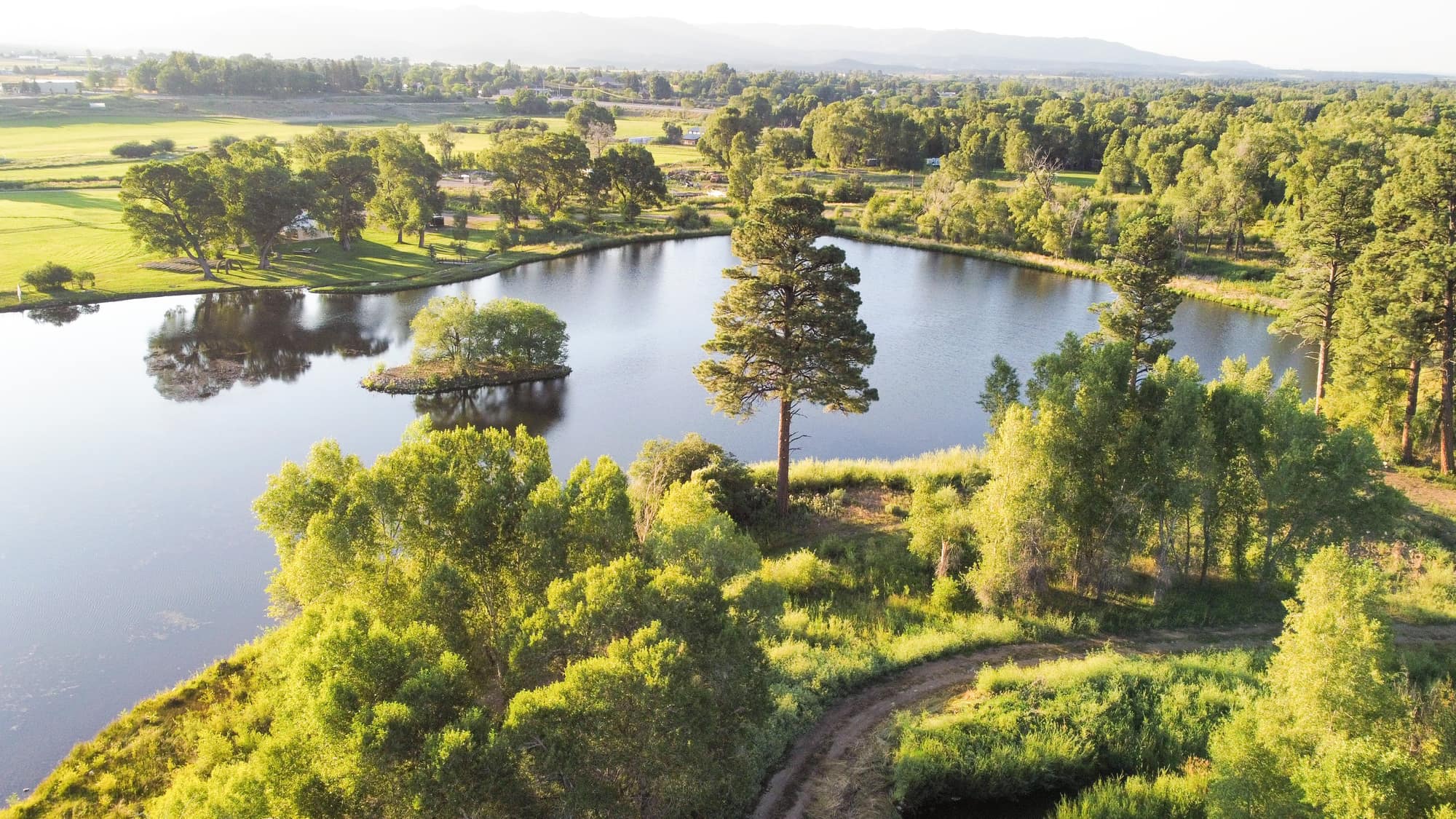Aerial drone view of LePlatt's Pond showing the 10-acre lake, tree-covered island, and surrounding Pine River Valley