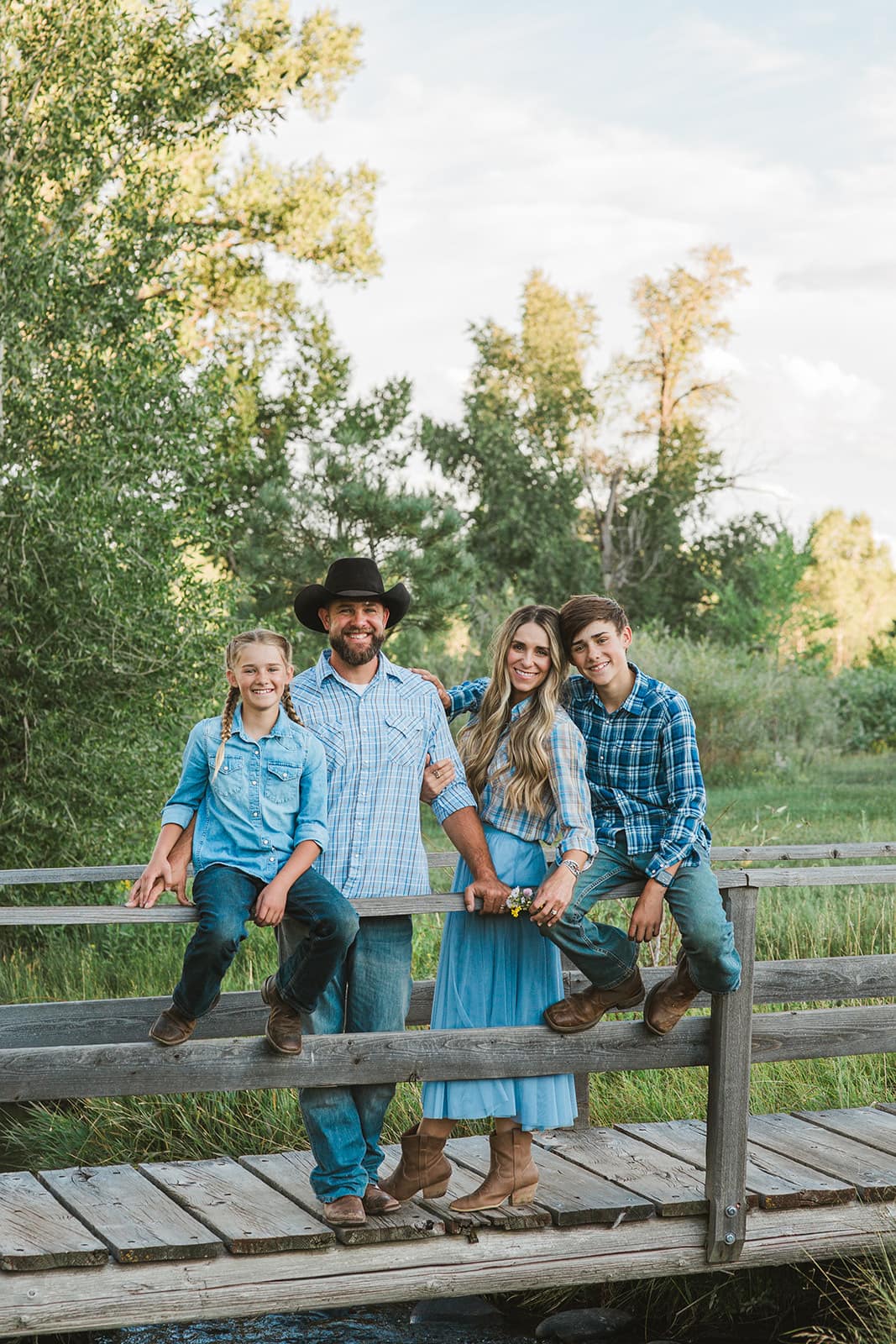 The Black family posing together on a rustic wooden bridge at L-J Ranch