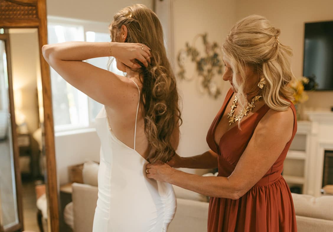 Bride having her dress zipped up by her mother in The Loft bridal suite