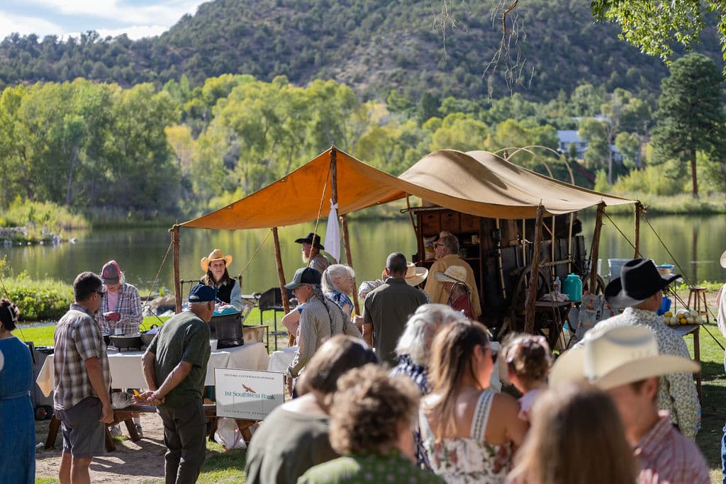 Guests gathering around chuckwagons beside the pond