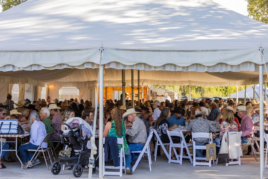 Community enjoying dinner together beneath a tent