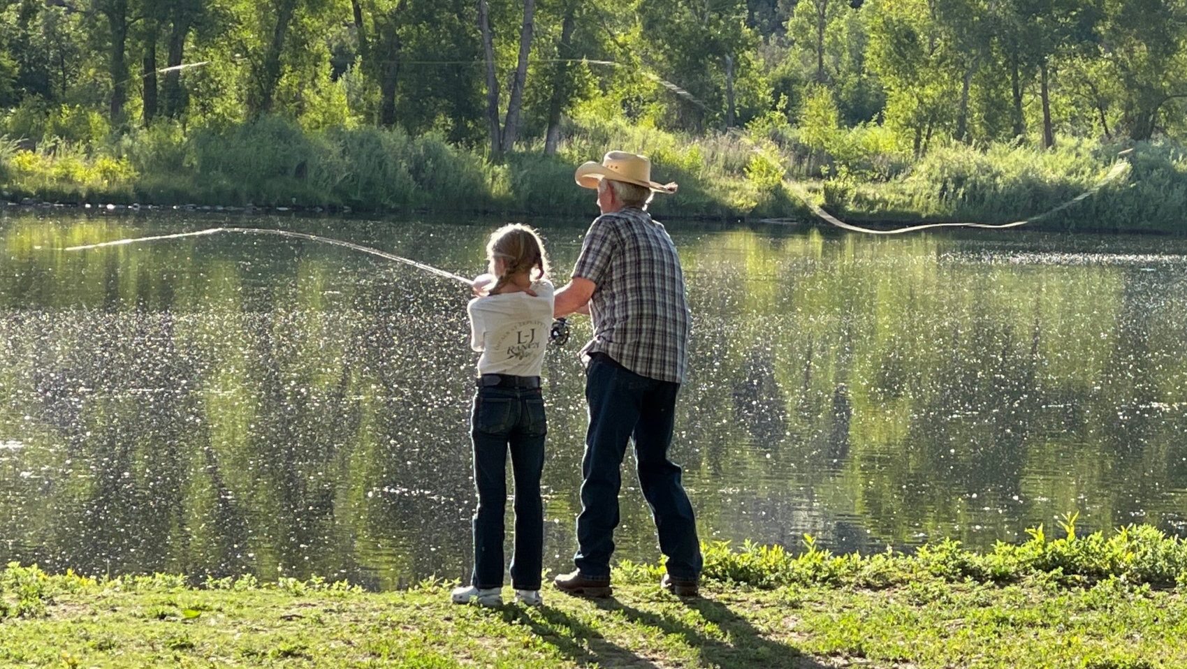 Grandfather and granddaughter casting a fishing line at the pond during Local's Night