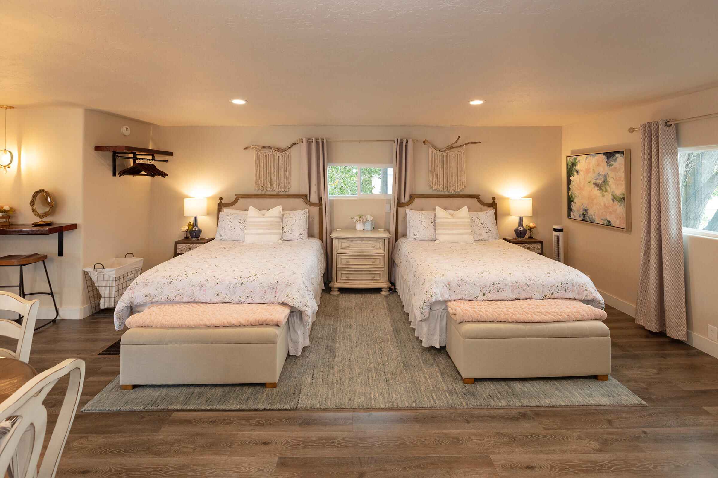 The Loft two queen beds with floral bedding, pink throws, and macrame wall hangings