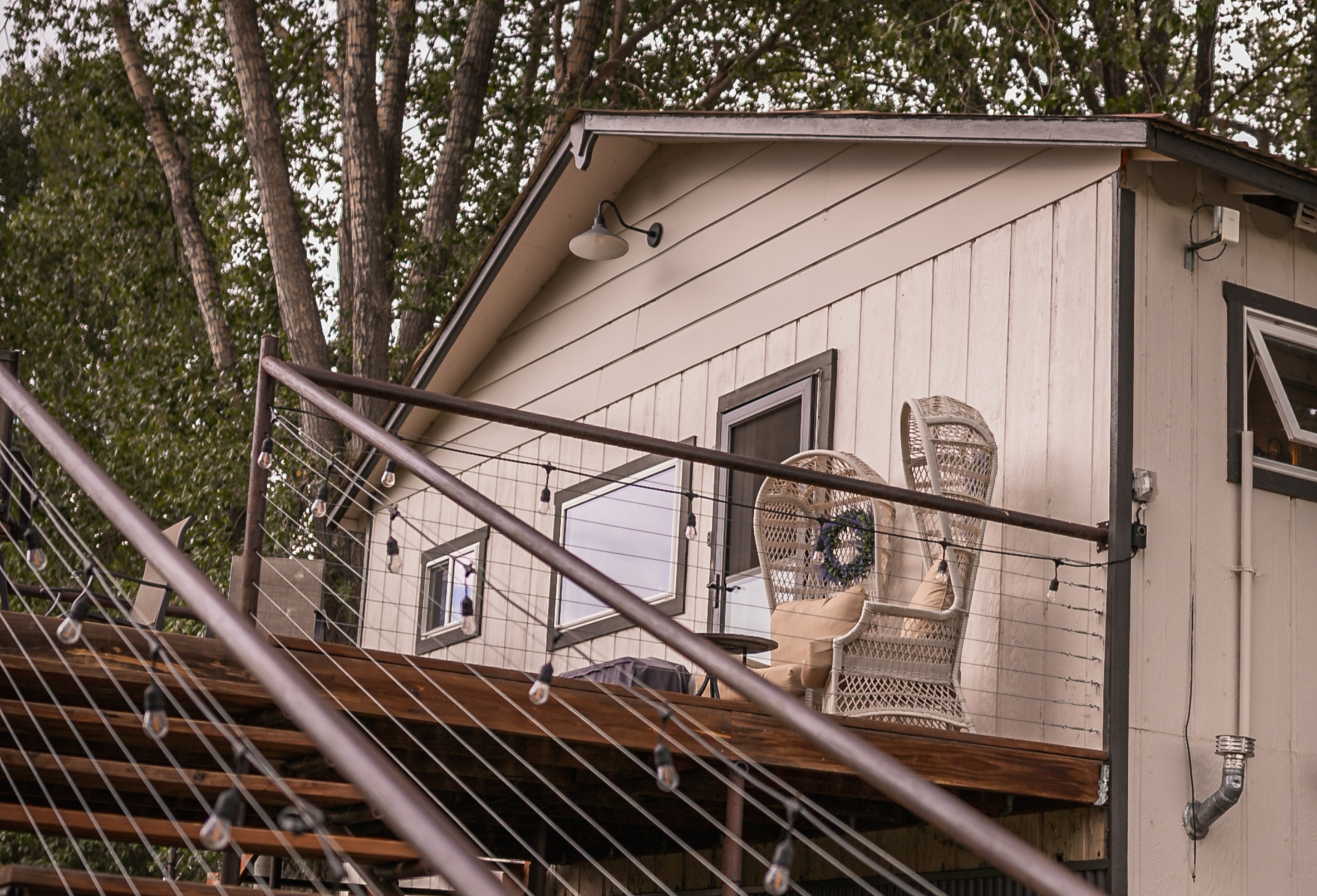 The Loft exterior showing wooden staircase with string lights and deck chairs