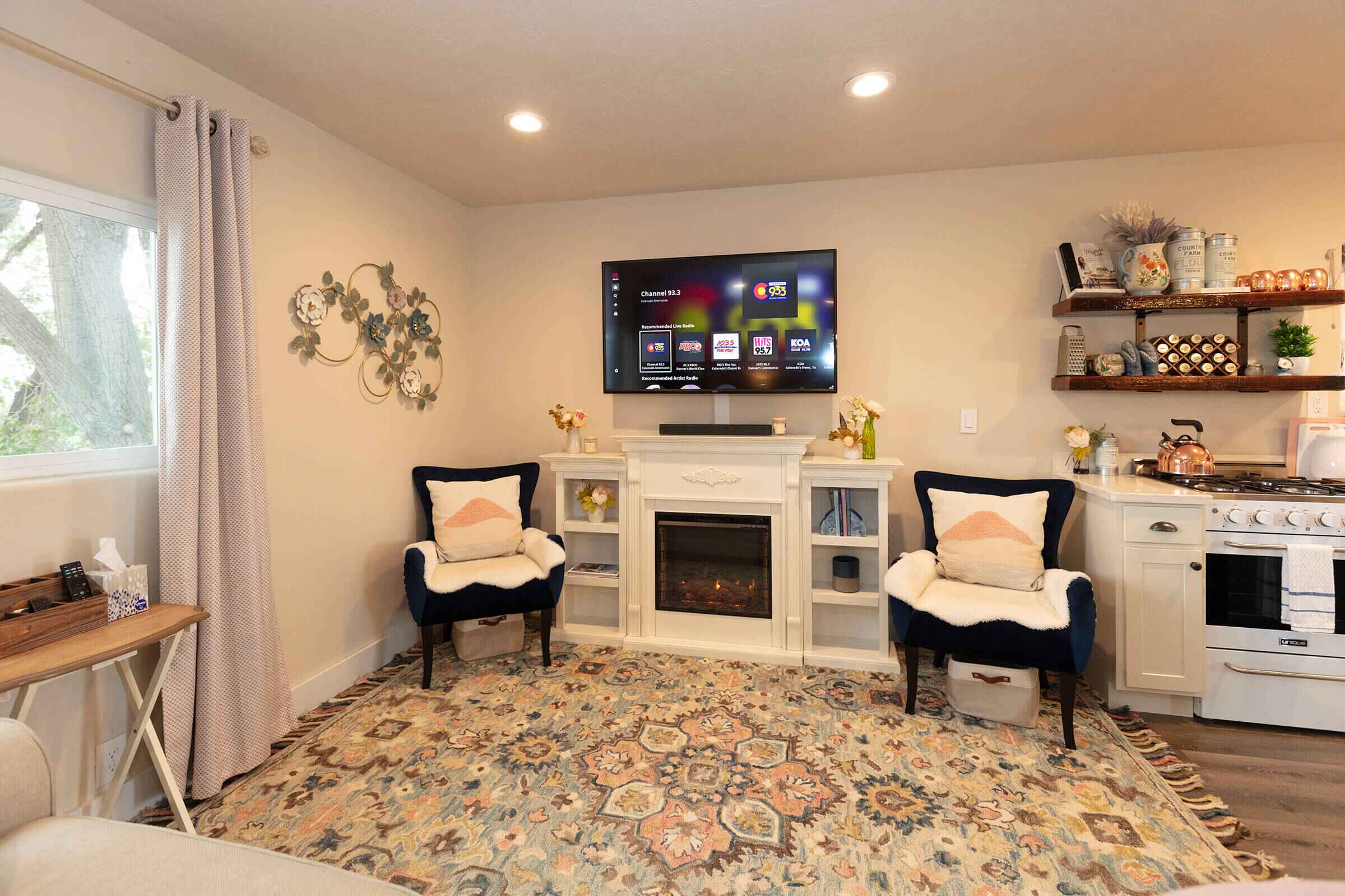 The Loft living area with electric fireplace, navy wingback chairs, smart TV, and kitchenette