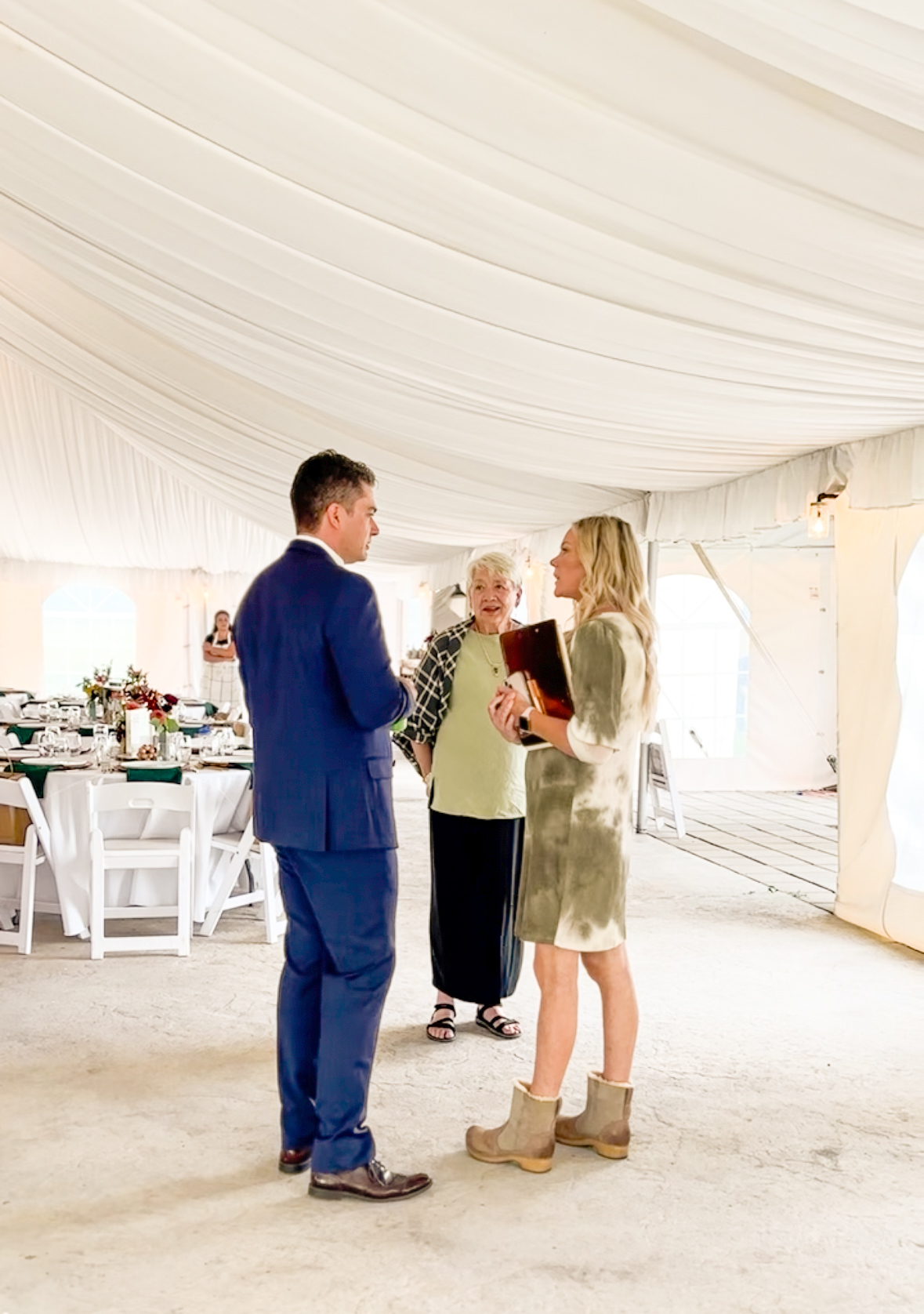 Day-of coordinator Lacy reviewing the timeline with a clipboard inside the draped reception tent