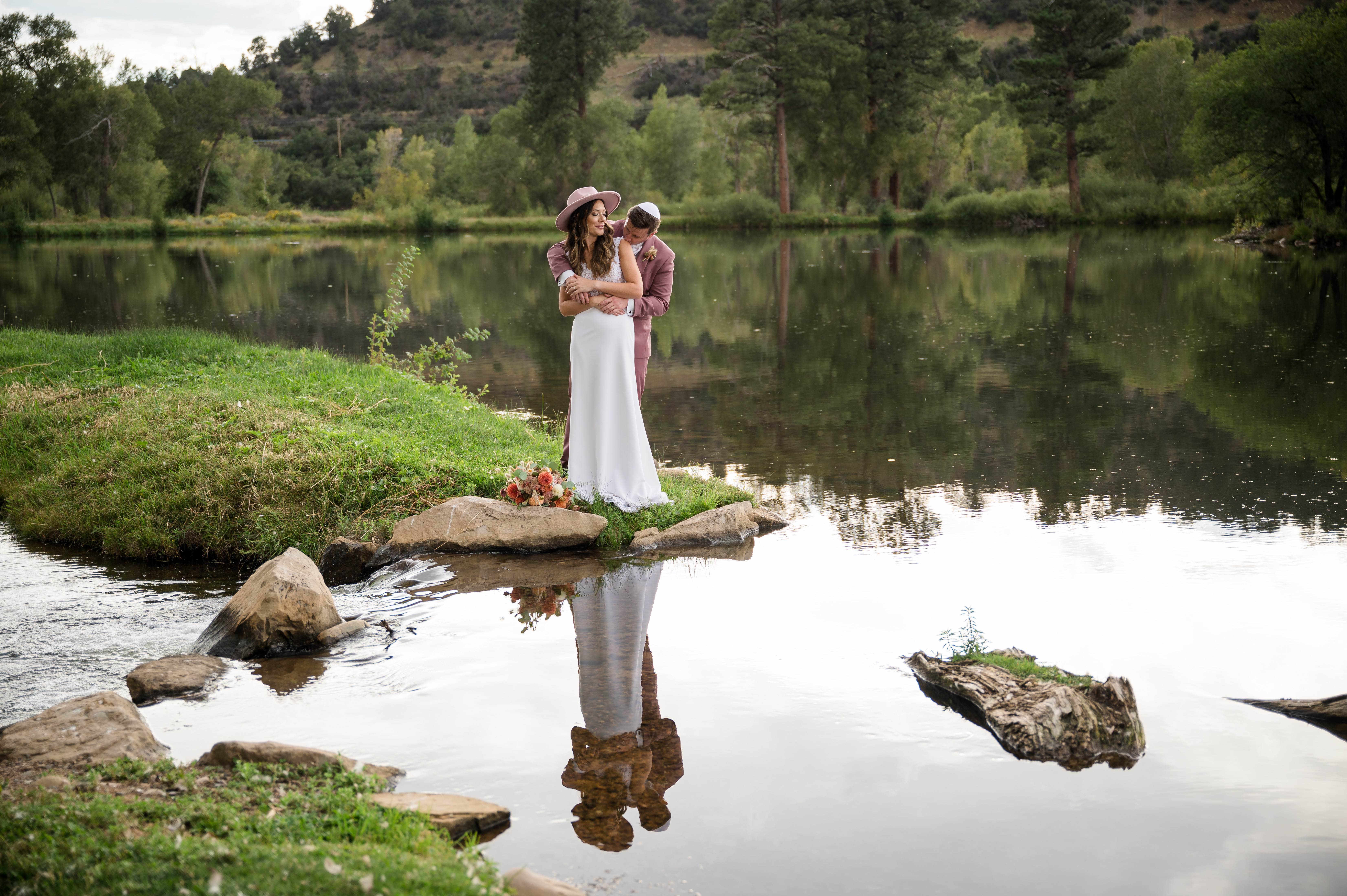 Romantic couple portrait by the pond with mountain reflections in still water
