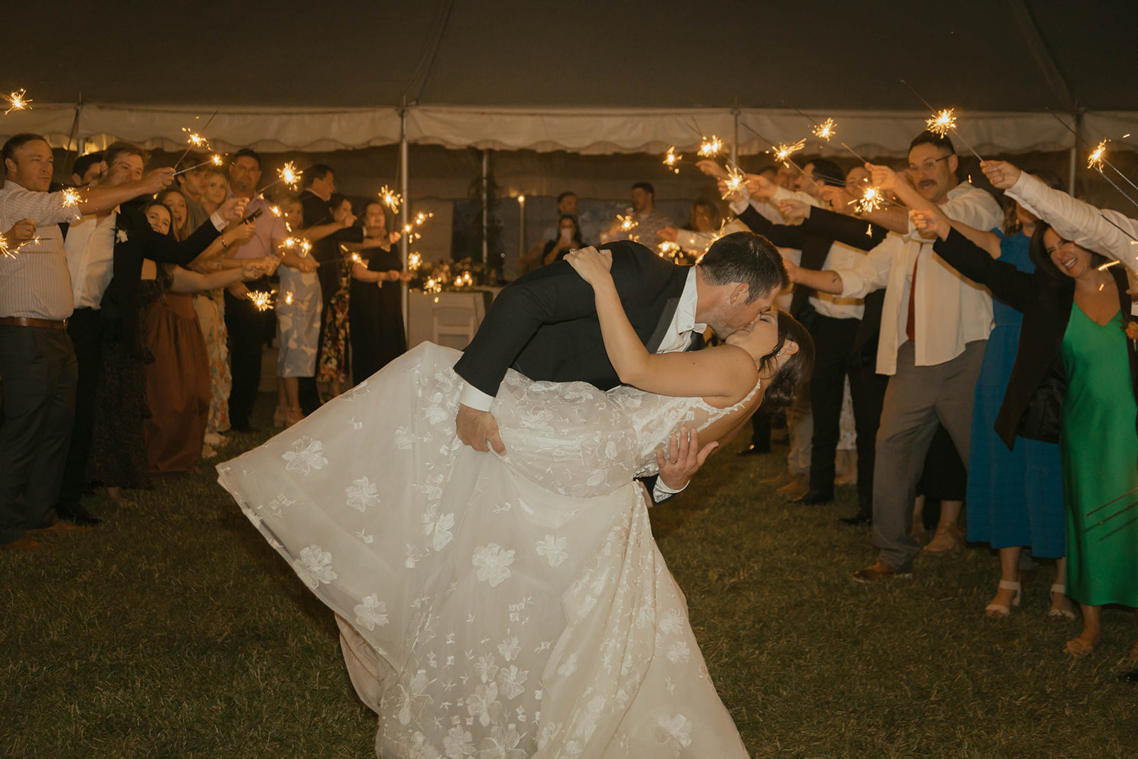 Sparkler exit with groom dipping bride for a kiss as guests line both sides holding sparklers